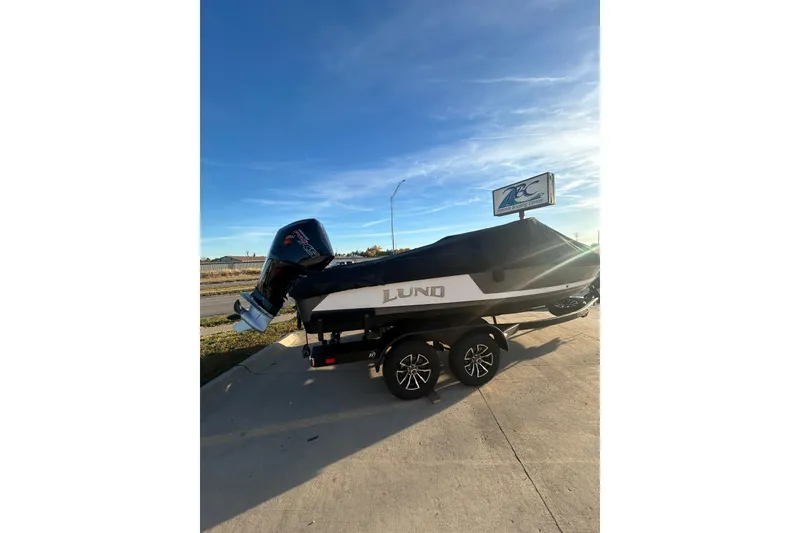 Slide: The Image of 2026 Lund 202 Pro-V GL boat on trailer under clear blue sky. - 11