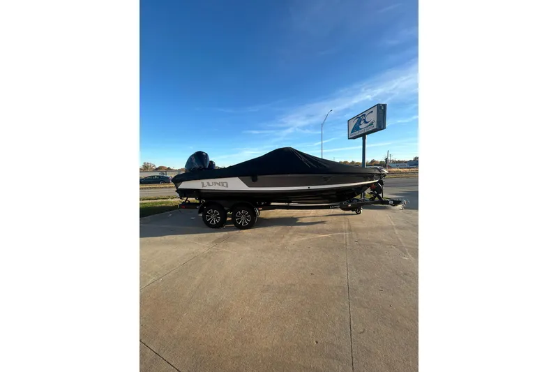 Slide: The Image of 2026 Lund 202 Pro-V GL boat on trailer, covered, parked outdoors. - 12