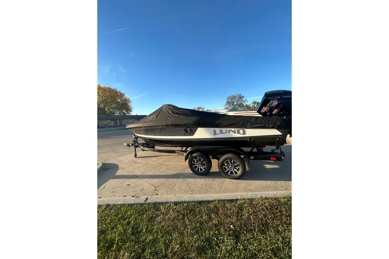 Slide: The Image of 2026 Lund 202 Pro-V GL boat on trailer, covered, parked outdoors. - 13