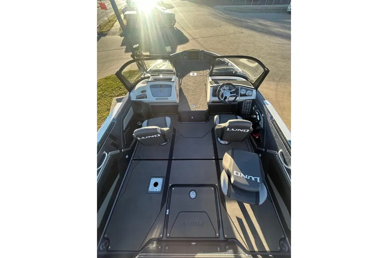 Slide: The Image of 2026 Lund 202 Pro-V GL boat interior with steering wheel and seating in sunlight. - 15