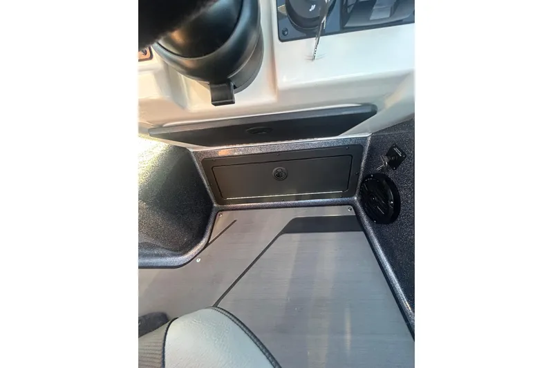 Slide: The Image of 2026 Lund 202 Pro-V GL boat interior dashboard with storage compartment and speaker. - 21
