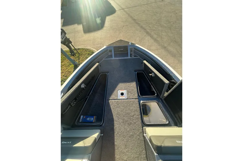 Slide: The Image of 2026 Lund 202 Pro-V GL boat interior with open storage compartments and sunlight. - 29