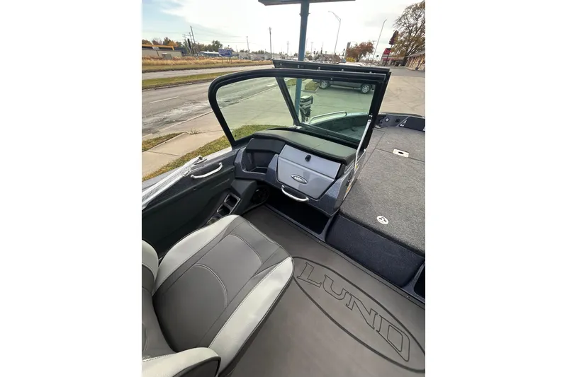 Slide: The Image of 2026 Lund 219 Pro-V GL boat on trailer, parked outdoors under cloudy sky. - 13