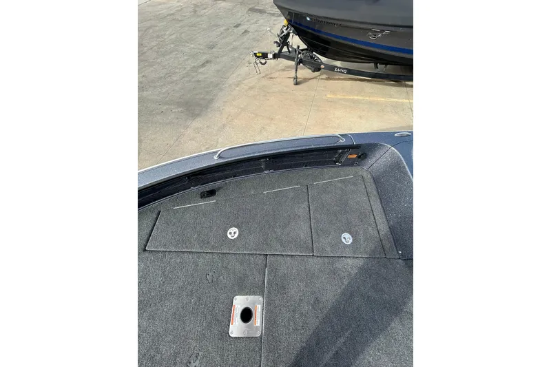 Slide: The Image of 2026 Lund 219 Pro-V GL boat with cover, parked outdoors near Safelite AutoGlass sign. - 19