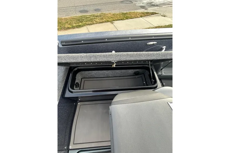 Slide: The Image of 2026 Lund 219 Pro-V GL boat interior storage compartment, open lid, outdoor setting. - 24