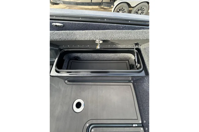 Slide: The Image of 2026 Lund 219 Pro-V GL boat storage compartment with coiled hose and cup holder. - 33