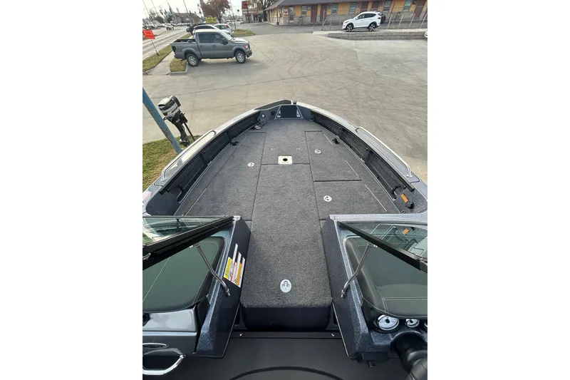 Slide: The Image of 2026 Lund 219 Pro-V GL boat interior with seating and storage, parked near a road. - 37