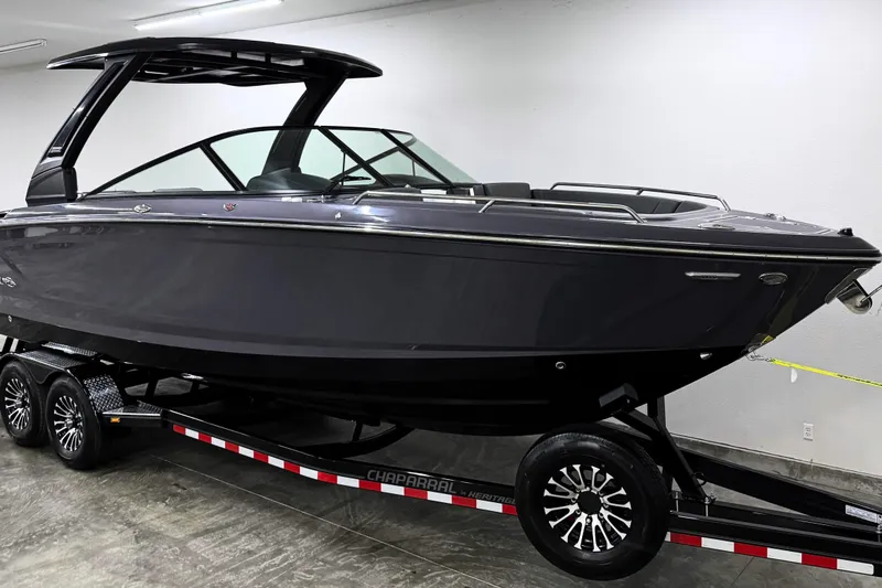 Slide: The Image of 2026 Chaparral 30 SSX boat on trailer in showroom, sleek black design. - 2