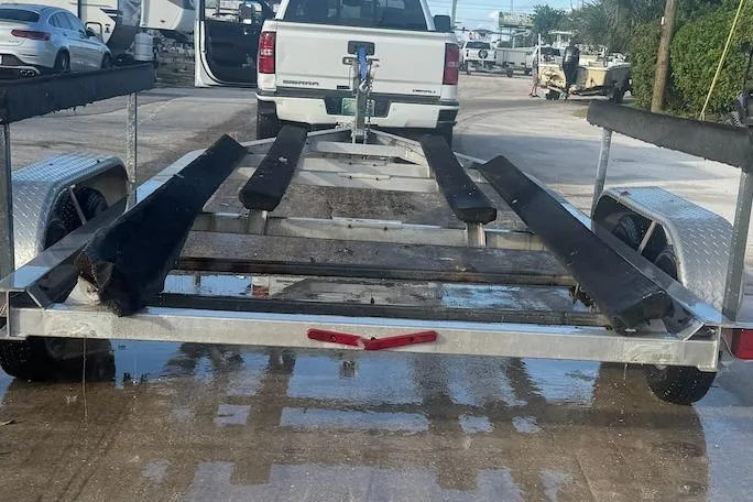 Slide: The Image of Boat trailer for a 2013 Carolina Skiff 218 DLV, parked on a wet surface. - 2