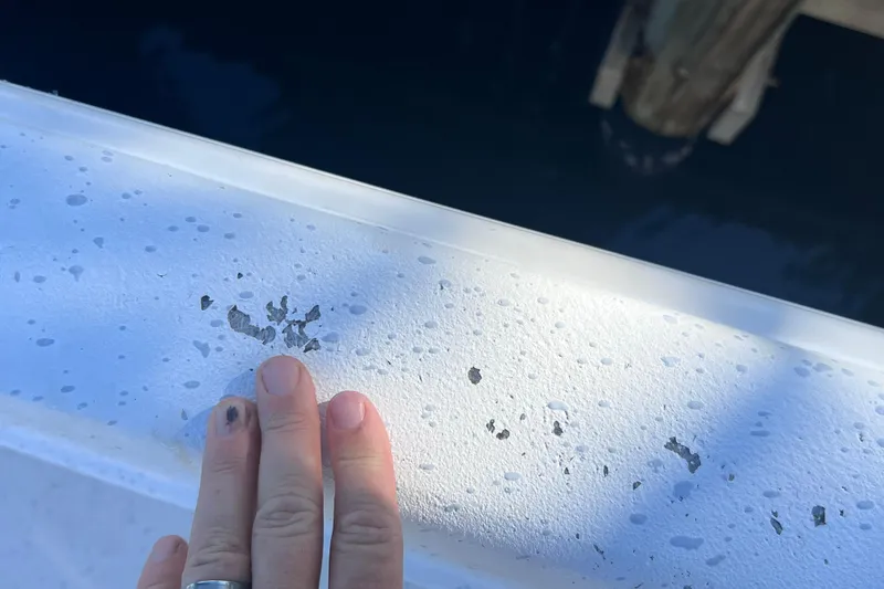 Slide: The Image of Close-up of 2013 Carolina Skiff 218 DLV with chipped paint and hand touching surface. - 39