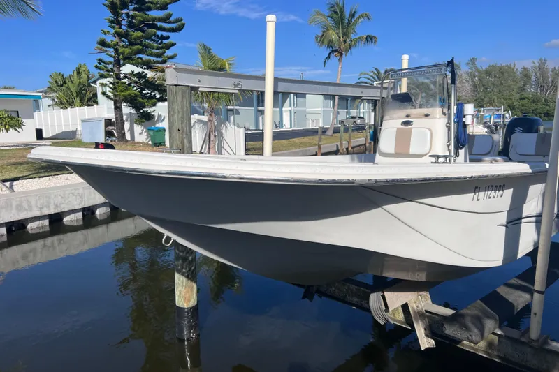 Slide: The Image of 2013 Carolina Skiff 218 DLV boat on lift, docked near waterfront homes. - 5