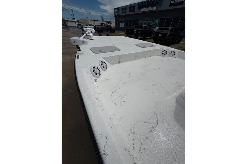Slide: The Image of 2023 Shoalwater 23 Catamaran boat deck with speakers and trolling motor, parked outside dealership. - 11