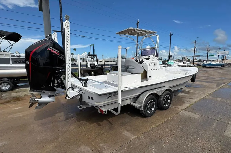 Slide: The Image of 2023 Shoalwater 23 Catamaran with outboard motor on trailer, parked outdoors. - 18