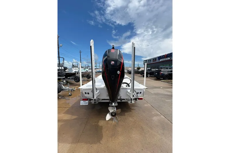 Slide: The Image of 2023 Shoalwater 23 Catamaran with outboard motor, parked on a trailer under a cloudy sky. - 2