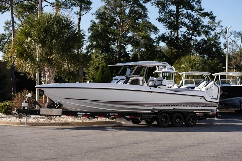 The Image of 2026 Sunsation 32 CCX boat on trailer, parked outdoors with trees in background. - 1