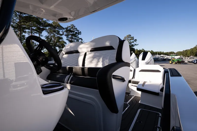 Slide: The Image of 2026 Sunsation 32 CCX boat interior with sleek white and black seating, steering wheel, and outdoor setting. - 14