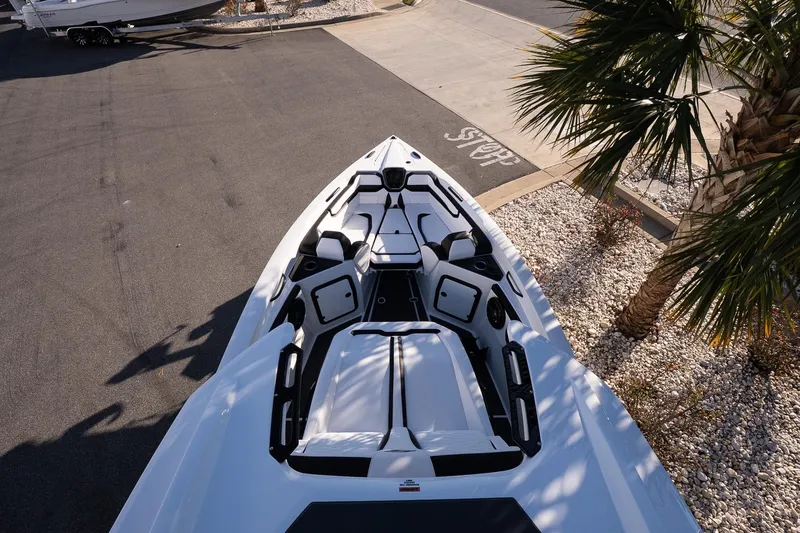 Slide: The Image of 2026 Sunsation 32 CCX boat with sleek white seating and modern design, parked near palm trees. - 19