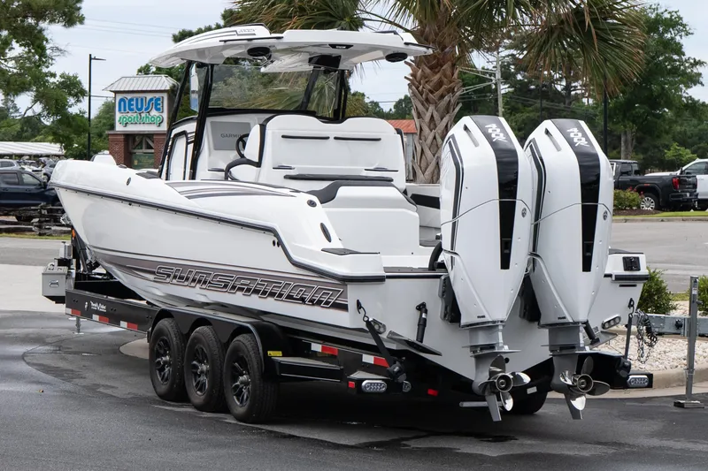 Slide: The Image of 2026 Sunsation 32 CCX boat with dual engines on a trailer, parked near palm trees. - 28