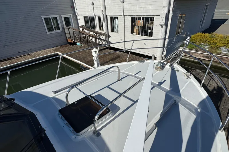 Slide: The Image of 1991 Ocean Alexander 46 yacht bow with railing, docked near wooden buildings. - 28