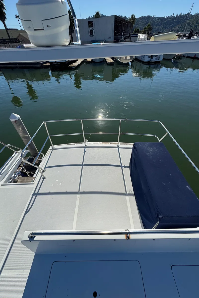 Slide: The Image of 1991 Ocean Alexander 46 yacht deck with railing, docked in a serene marina. - 33
