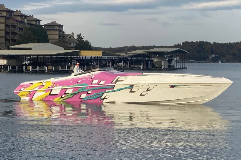 The Image of 1999 Black Thunder XT 430 SC boat with vibrant pink and yellow design on a calm lake. - 1