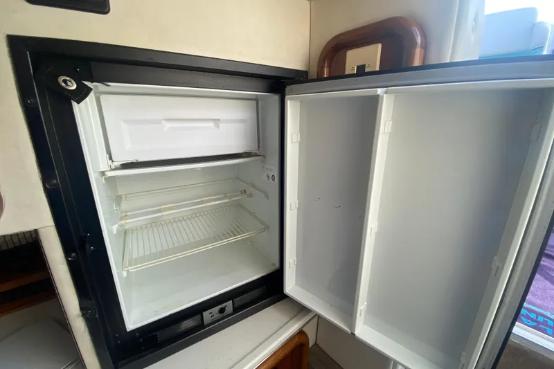 Slide: The Image of Open refrigerator inside a 1999 Black Thunder XT 430 SC boat, showing empty shelves. - 29