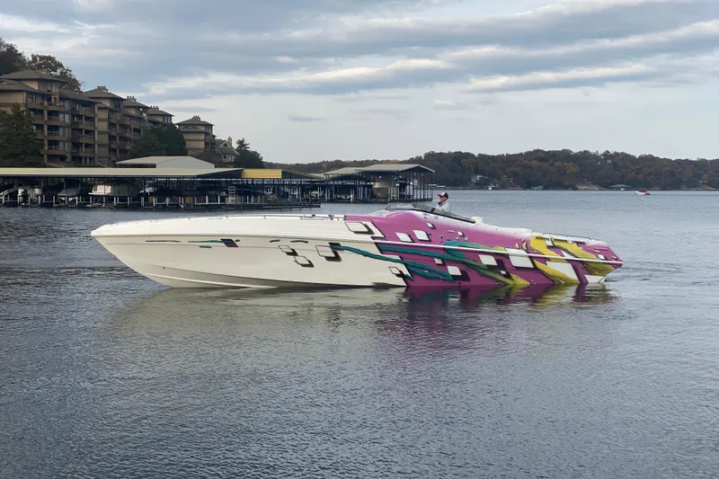 Slide: The Image of 1999 Black Thunder XT 430 SC boat with vibrant graphics on a calm lake. - 49