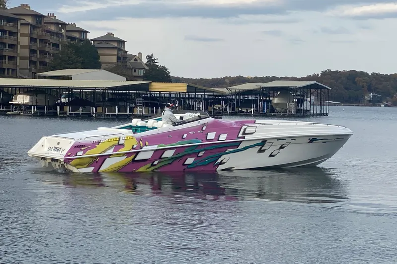 Slide: The Image of 1999 Black Thunder XT 430 SC boat with vibrant graphics on a calm lake. - 54