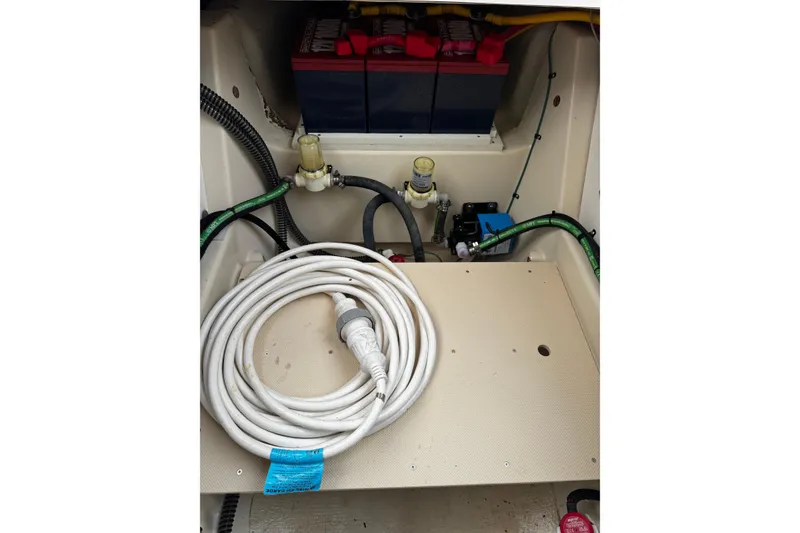 Slide: The Image of 2024 Ranger Tugs R-25 boat compartment with coiled cable and battery setup. - 10