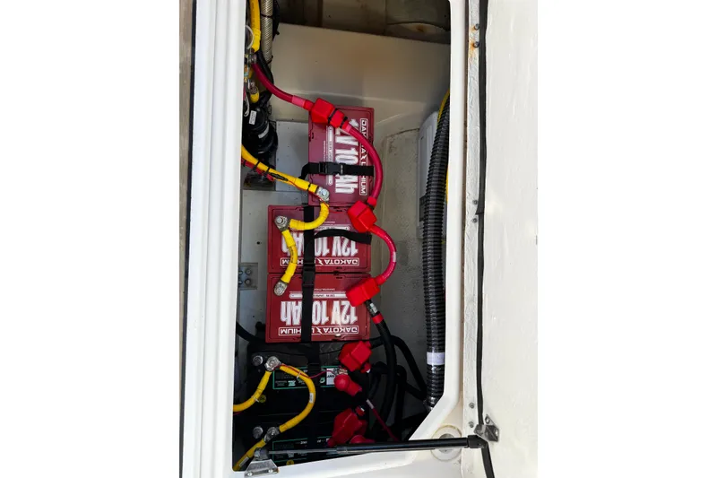 Slide: The Image of 2024 Ranger Tugs R-25 battery compartment with red and yellow cables. - 12