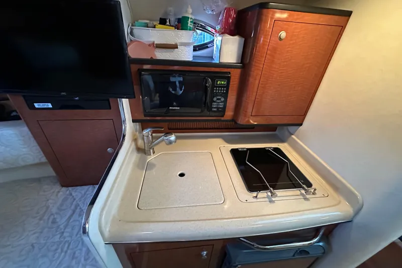 Slide: The Image of 2005 Sea Ray 280 Sundancer cabin kitchen with stove, sink, and microwave. - 17
