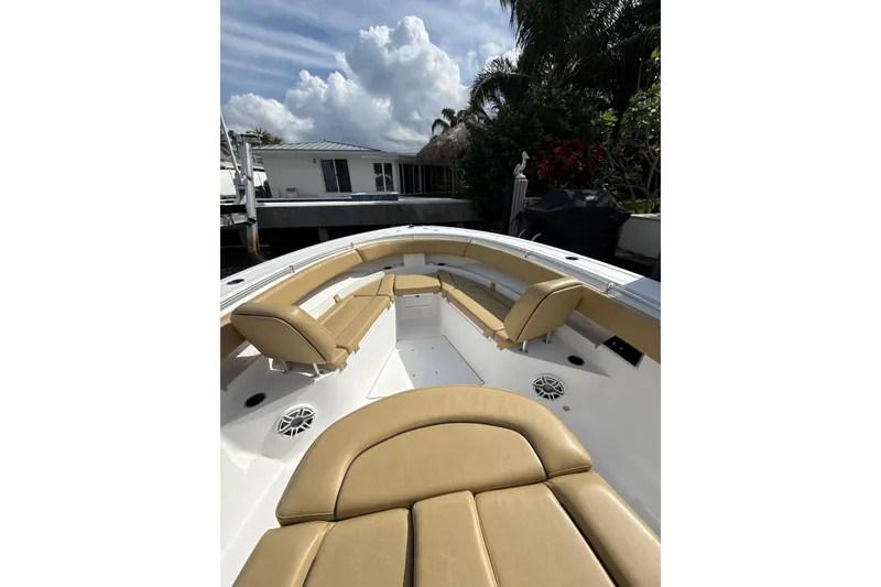 Slide: The Image of 2023 Sportsman Open 352 Center Console boat with tan seating, docked near a house. - 16