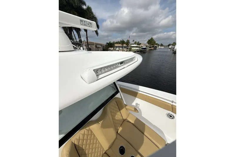 Slide: The Image of 2023 Sportsman Open 352 Center Console boat with tan seating, docked by a canal. - 58