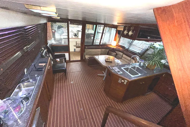 Slide: The Image of 1989 Bayliner 4588 Pilothouse interior with kitchen, seating area, and wooden flooring. - 11