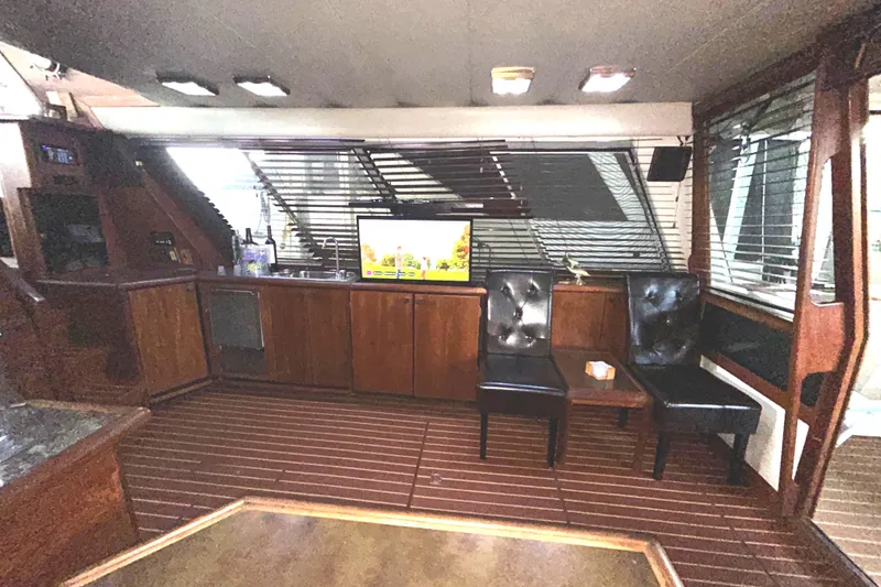Slide: The Image of Interior of 1989 Bayliner 4588 Pilothouse with wood paneling, TV, and leather chairs. - 14