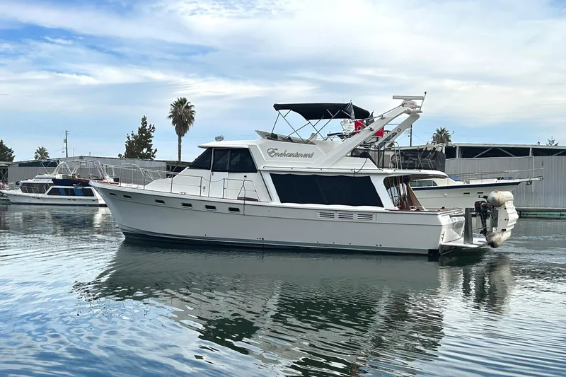Slide: The Image of 1989 Bayliner 4588 Pilothouse yacht docked on calm water, with marina background. - 3
