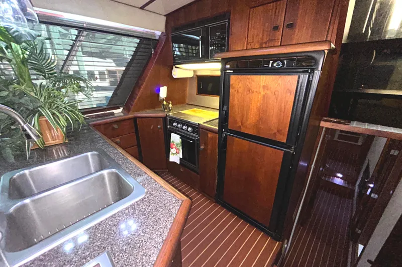 Slide: The Image of 1989 Bayliner 4588 Pilothouse galley with wood cabinetry, double sink, and appliances. - 31
