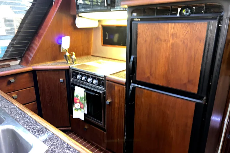 Slide: The Image of 1989 Bayliner 4588 Pilothouse kitchen with wood cabinetry and modern appliances. - 32