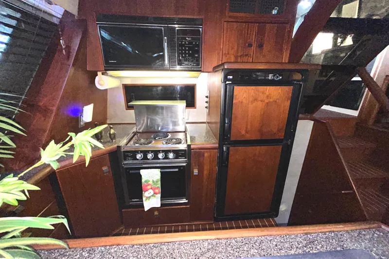 Slide: The Image of 1989 Bayliner 4588 Pilothouse kitchen with stove, microwave, and refrigerator. - 33