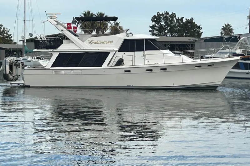 Slide: The Image of 1989 Bayliner 4588 Pilothouse yacht docked in a marina, reflecting on calm water. - 4