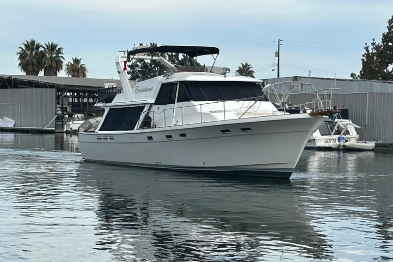 Slide: The Image of 1989 Bayliner 4588 Pilothouse yacht docked in a marina, surrounded by calm water. - 5