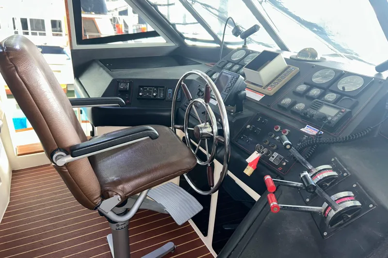 Slide: The Image of 1989 Bayliner 4588 Pilothouse helm with steering wheel, controls, and navigation instruments. - 64