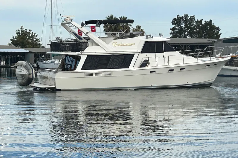 Slide: The Image of 1989 Bayliner 4588 Pilothouse yacht docked in a marina, reflecting on calm water. - 7