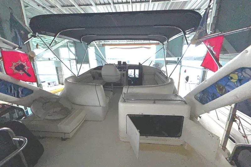 Slide: The Image of 1989 Bayliner 4588 Pilothouse interior with seating and canopy, docked in a covered marina. - 70