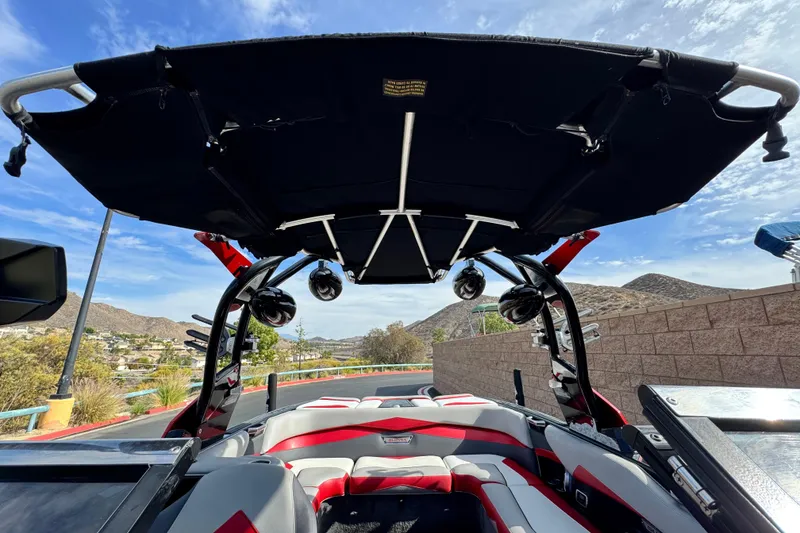 Slide: The Image of 2014 Supra SA350 boat with black canopy and red accents, parked near mountains. - 13