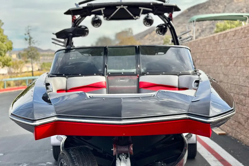 Slide: The Image of 2014 Supra SA350 boat with sleek design and red accents, parked outdoors. - 2