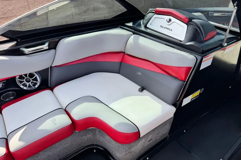 Slide: The Image of 2014 Supra SA350 boat interior with red and gray seating, speaker, and storage compartment. - 28