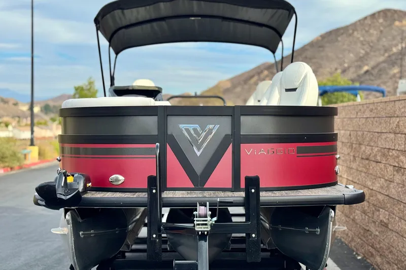 Slide: The Image of 2023 Viaggio Diamante 23E pontoon boat, red and black design, parked outdoors. - 2