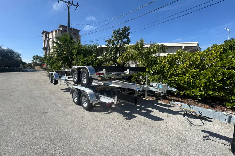 Slide: The Image of 2025 Trailers Trailer Mania parked on a sunny street with greenery. - 2