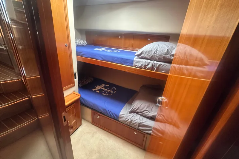 Slide: The Image of 2007 Riviera Sport Fisherman cabin with wooden bunk beds and blue bedding. - 17
